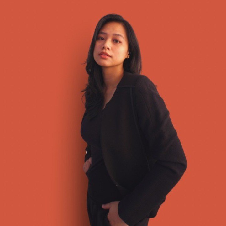 Maria Pe in a black blazer against a terracotta wall